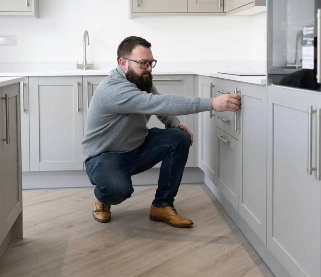 man inspecting kitchen cabinet handles in modern kitchen