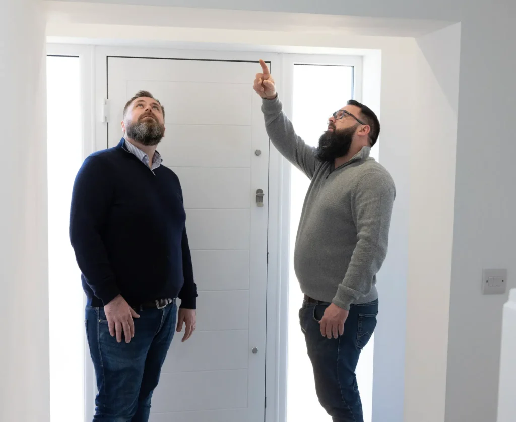 Two men discussing property evaluation while looking at the ceiling.