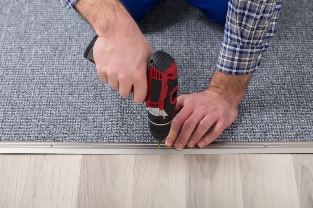 close-up of a person using a drill for carpet installation